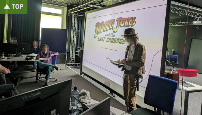   Referent im Indiana-Jones-Look hält Vortrag   