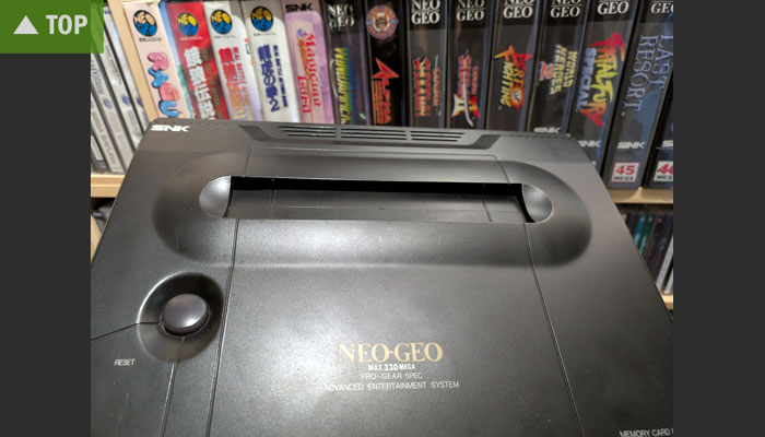 Neo-Geo-Konsole mit Spielepackungen im Hintergrund